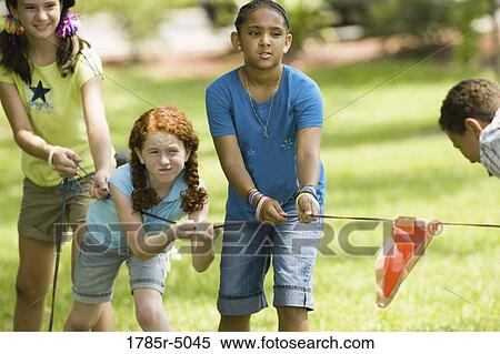 Three girls pulling hard at tug-of-war at a park View Large Photo Image Stock Photography - Three girls pulling hard at tug-of-war at a park. Fotosearch