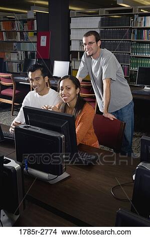 Picture - Three university students using computers in the library. Fotosearch
