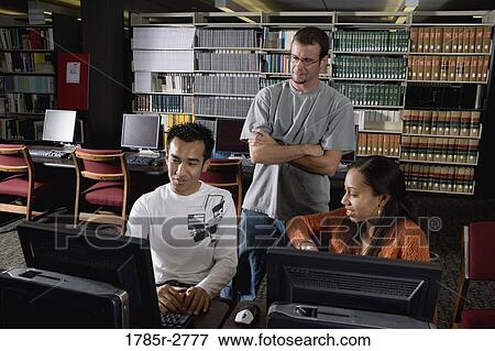 Three university students using computers in the library View Large Photo Image Stock Photo - Three university students using computers in the library. Fotosearch