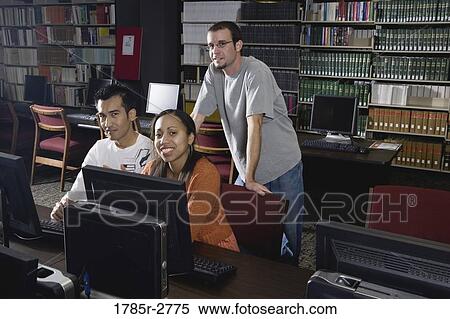 Stock Photography - Three university students using computers in the library. Fotosearch