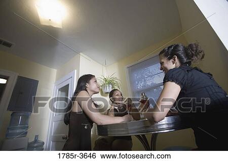 Stock Photograph - Three women having drinks in kitchen. Fotosearch