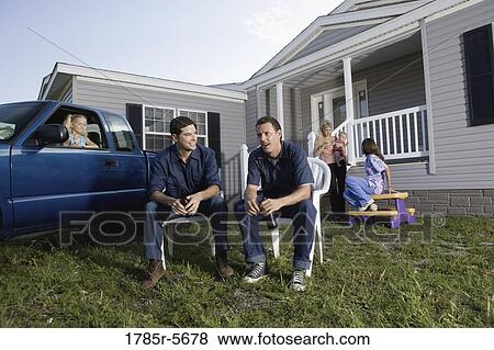 Two blue-collar men holding cold drinks sitting on lawn chairs in front of trailer home View Large Photo Image Stock Photo - Two blue-collar men holding cold drinks sitting on lawn chairs in front of trailer home. Fotosearch