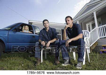 Two blue-collar men relaxing with drinks sitting on front lawn of house View Large Photo Image Stock Photograph - Two blue-collar men relaxing with drinks sitting on front lawn of house. Fotosearch