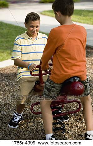 Two boys playing on a see-saw at a playground View Large Photo Image Stock Photo - Two boys playing on a see-saw at a playground. Fotosearch