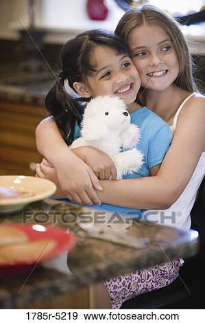 Two cheerful sisters hugging and playing View Large Photo Image Stock Photo - Two cheerful sisters hugging and playing. Fotosearch