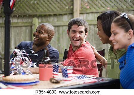 Two couples sitting at table on backyard patio on 4th of July View Large Photo Image Stock Image - Two couples sitting at table on backyard patio on 4th of July. Fotosearch