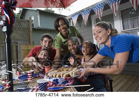 Two families on backyard patio enjoying a cookout on the 4th of July View Large Photo Image Picture - Two families on backyard patio enjoying a cookout on the 4th of July. Fotosearch