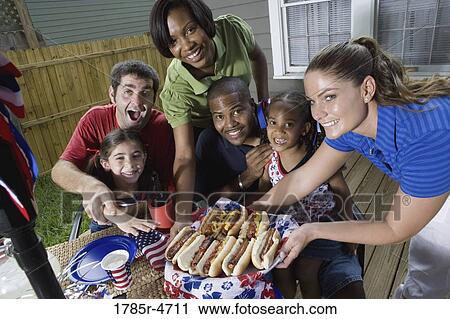 Stock Image - Two families on backyard patio enjoying a cookout on the 4th of July. Fotosearch