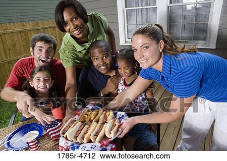 Two families on backyard patio enjoying a cookout on the 4th of July View Large Photo Image Stock Image - Two families on backyard patio enjoying a cookout on the 4th of July. Fotosearch