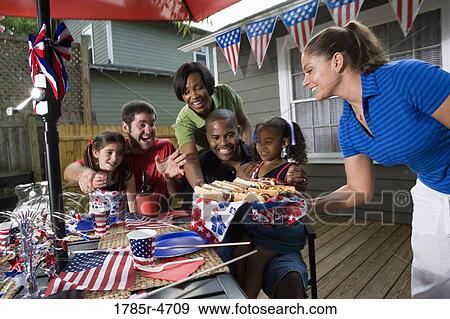 Two families on backyard patio enjoying a cookout on the 4th of July View Large Photo Image Stock Photo - Two families on backyard patio enjoying a cookout on the 4th of July. Fotosearch
