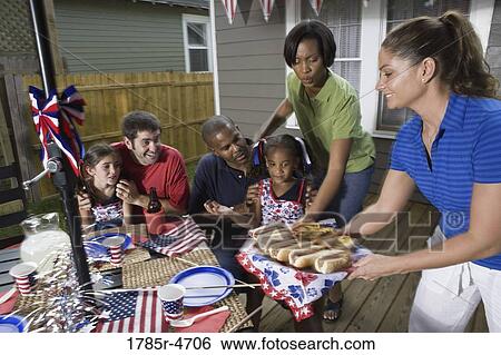 Two families on backyard patio enjoying a cookout on the 4th of July View Large Photo Image Stock Photograph - Two families on backyard patio enjoying a cookout on the 4th of July. Fotosearch