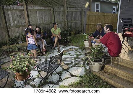 Two families on backyard patio relaxing with cold drinks View Large Photo Image Stock Image - Two families on backyard patio relaxing with cold drinks. Fotosearch