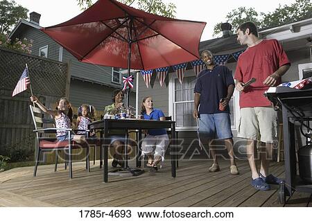 Two families on backyard patio celebrating 4th of July View Large Photo Image Stock Image - Two families on backyard patio celebrating 4th of July. Fotosearch