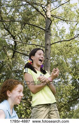 Two girls laughing together at a park View Large Photo Image Stock Photo - Two girls laughing together at a park. Fotosearch