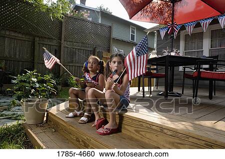 Stock Image - Two little girls in backyard celebrating the 4th of July. Fotosearch
