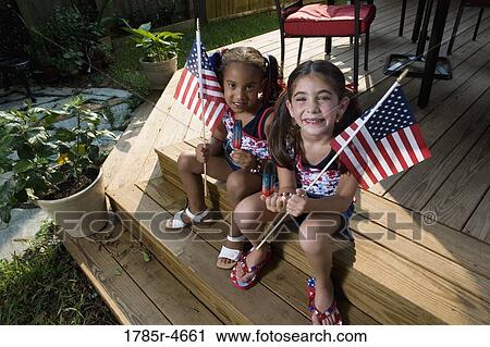 Two little girls in backyard celebrating the 4th of July View Large Photo Image Stock Image - Two little girls in backyard celebrating the 4th of July. Fotosearch