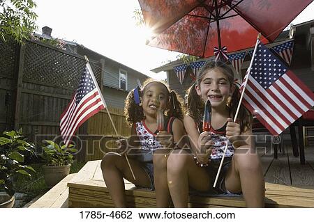 Two little girls in backyard celebrating the 4th of July View Large Photo Image Stock Image - Two little girls in backyard celebrating the 4th of July. Fotosearch