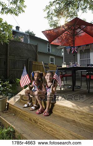 Two little girls in backyard celebrating the 4th of July View Large Photo Image Stock Image - Two little girls in backyard celebrating the 4th of July. Fotosearch