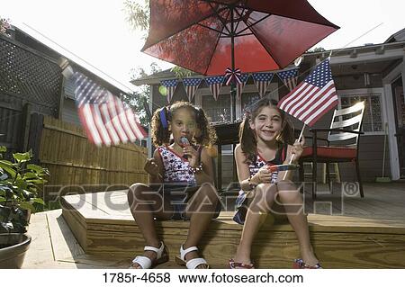 Two little girls in backyard celebrating the 4th of July View Large Photo Image Stock Photo - Two little girls in backyard celebrating the 4th of July. Fotosearch