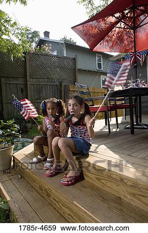 Two little girls in backyard celebrating the 4th of July View Large Photo Image Stock Photo - Two little girls in backyard celebrating the 4th of July. Fotosearch