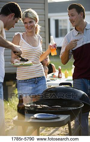 Two men and a woman enjoying a cookout in front of a trailer home View Large Photo Image Stock Image - Two men and a woman enjoying a cookout in front of a trailer home. Fotosearch