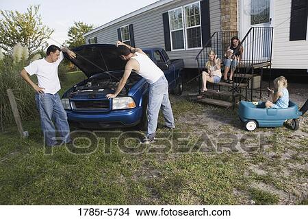 Two men looking under the hood of a pickup truck in front of trailer home View Large Photo Image Picture - Two men looking under the hood of a pickup truck in front of trailer home. Fotosearch