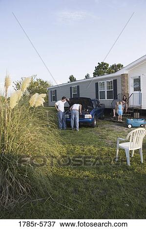 Two men looking under the hood of a pickup truck in front of trailer home View Large Photo Image Stock Photo - Two men looking under the hood of a pickup truck in front of trailer home. Fotosearch