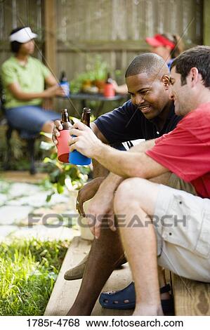 Two men sitting on steps of backyard patio enjoying cold beverages View Large Photo Image Stock Photo - Two men sitting on steps of backyard patio enjoying cold beverages. Fotosearch