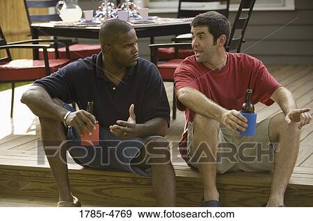 Two men sitting on steps of backyard patio enjoying cold beverages View Large Photo Image Stock Photo - Two men sitting on steps of backyard patio enjoying cold beverages. Fotosearch