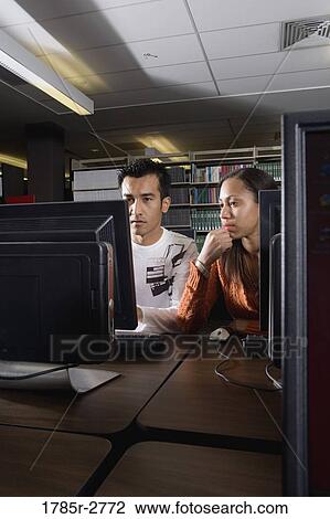 Stock Image - Two university students using computers in the library. Fotosearch