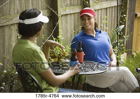 Two women sitting at table in backyard conversing View Large Photo Image Picture - Two women sitting at table in backyard conversing. Fotosearch