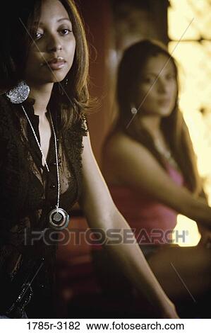Stock Image - Two young attractive women sitting. Fotosearch