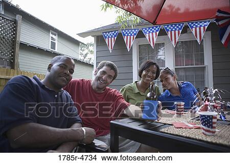 Picture - Two young couples on backyard patio on 4th of July. Fotosearch