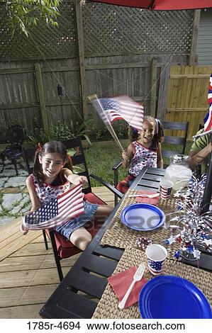 Two young girls at 4th of July cookout waving American flags View Large Photo Image Picture - Two young girls at 4th of July cookout waving American flags. Fotosearch