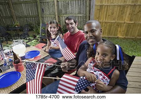 Two young girls with dads at 4th of July cookout waving American flags View Large Photo Image Stock Image - Two young girls with dads at 4th of July cookout waving American flags. Fotosearch