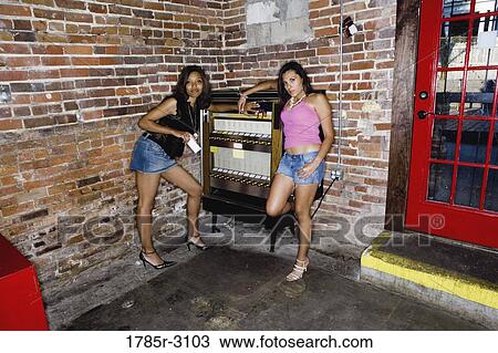 Two young women in hip-hop fashion standing suggestively at cigarette vending machine View Large Photo Image Stock Image - Two young women in hip-hop fashion standing suggestively at cigarette vending machine. Fotosearch