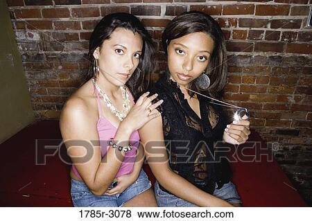 Stock Photo - Two young women in hip-hop fashion sitting suggestively. Fotosearch