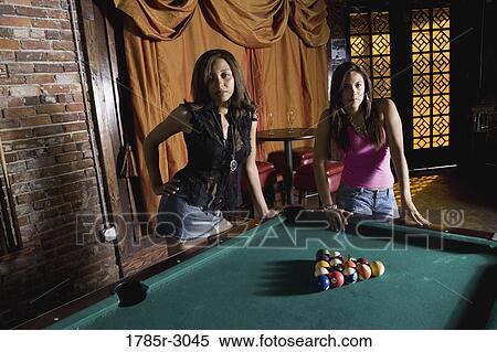 Two young women leaning against a pool table in a dimly lit bar View Large Photo Image Stock Photography - Two young women leaning against a pool table in a dimly lit bar. Fotosearch