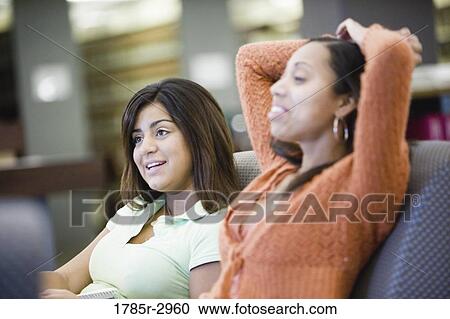Stock Image - Two young women relaxing on the sofa. Fotosearch
