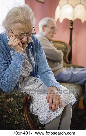 Upset elderly couple sitting on sofa View Large Photo Image Stock Photo - Upset elderly couple sitting on sofa. Fotosearch