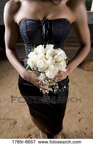 View below the shoulders of a woman in black holding a bouquet of white roses View Large Photo Image Stock Photo - View below the shoulders of a woman in black holding a bouquet of white roses. Fotosearch