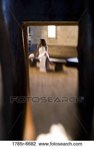 View of a bride in white holding a white bouquet seen through a doorway View Large Photo Image Stock Image - View of a bride in white holding a white bouquet seen through a doorway. Fotosearch