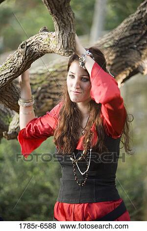 Stock Photo - View of a contemplative woman pirate standing under the tree. Fotosearch