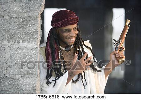 View of a smiling pirate armed with a pistol leaning against a castle wall View Large Photo Image Stock Photograph - View of a smiling pirate armed with a pistol leaning against a castle wall. Fotosearch