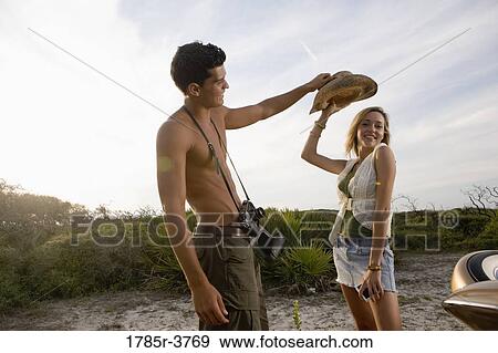 Stock Photo - View of a young couple playfully putting hat on. Fotosearch