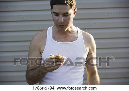 View of a young man eating a burger View Large Photo Image Picture - View of a young man eating a burger. Fotosearch