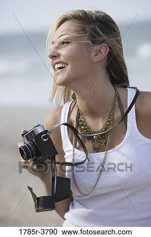 View of a young woman holding a camera View Large Photo Image Stock Image - View of a young woman holding a camera. Fotosearch
