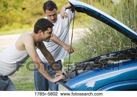 Stock Image - View of two men inspecting a car engine. Fotosearch