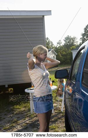 Woman fixing her hair using parked car's window as mirror View Large Photo Image Stock Photo - Woman fixing her hair using parked car's window as mirror. Fotosearch