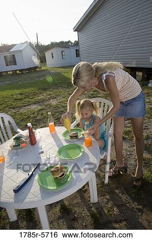 Woman helping girl with her food at a picnic table outside trailer homes View Large Photo Image Stock Photograph - Woman helping girl with her food at a picnic table outside trailer homes. Fotosearch